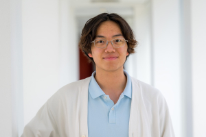 A student wearing white and blue in a white hallway.