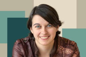 Smiling young woman with short hair and blue eyes, wearing a brown leather jacket, posing confidently for a portrait.