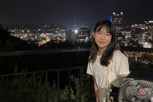 Yunfei Niu poses in front of the Pittsburgh skyline.