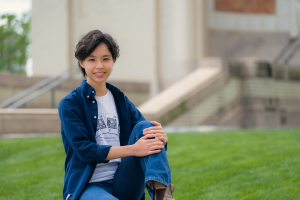 Yuqing Lin sits outside of Hamerschlag Hall and smiles at the camera.