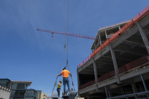 The last steel beam of the Richard King Mellon building is hoisted into place, “topping off” the facility’s structural phase.