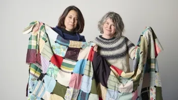 Two women holding up a quilt