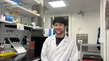 Riley Santiago sits in a biology lab and smiles at the camera.