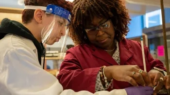 A faculty member stirs a beaker while a student watches.