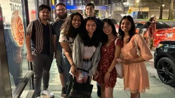 Image of a group of students posing on a sidewalk at night.